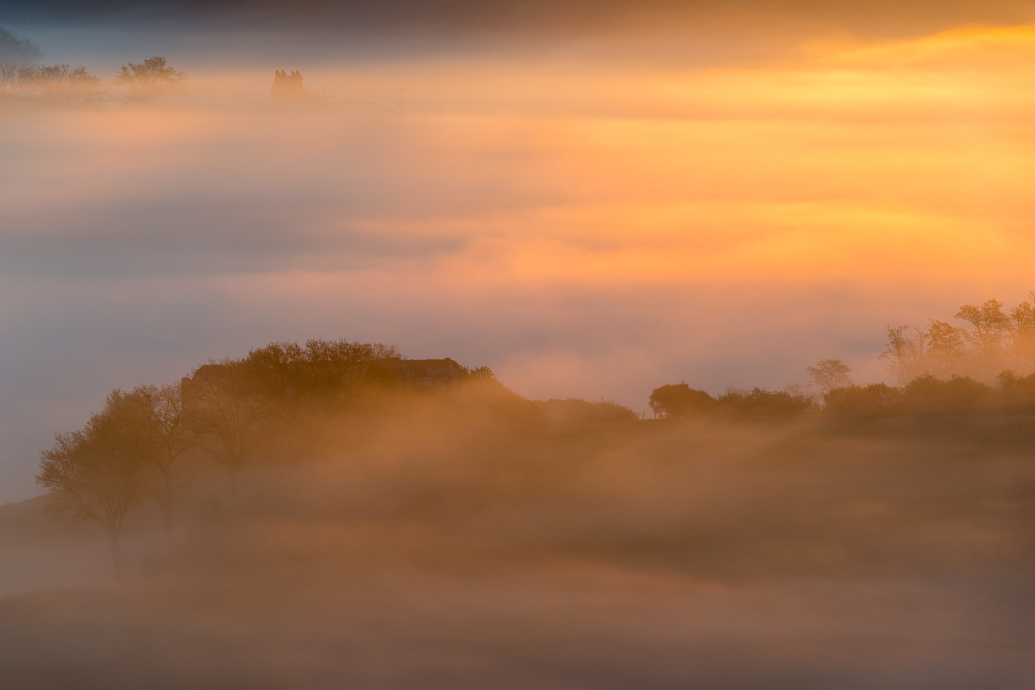 Casali nella nebbia nei pressi di Asciano, cuore delle Crete Senesi. Toscana (Siena)