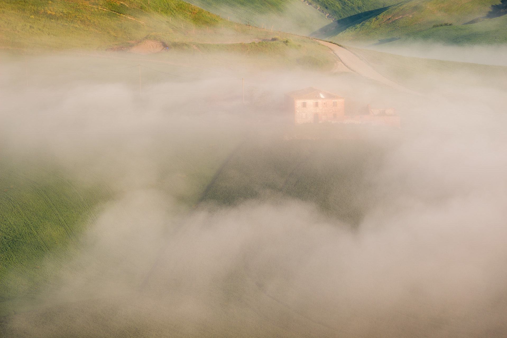 Casali nella nebbia nei pressi di Asciano, cuore delle Crete Senesi. Toscana (Siena)